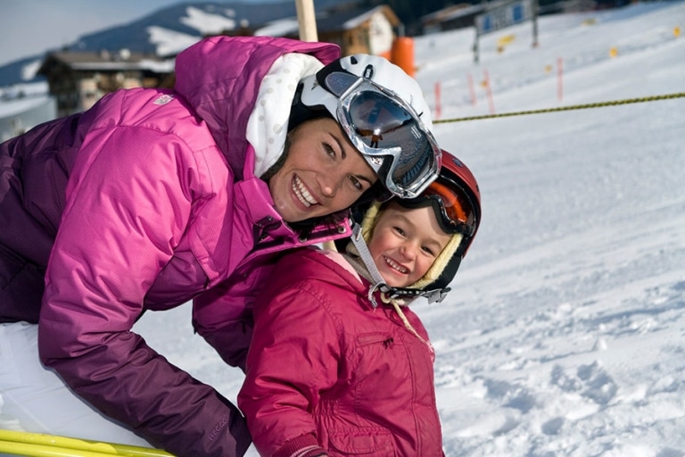 Mutter mit Kind in Skianzug im Winter