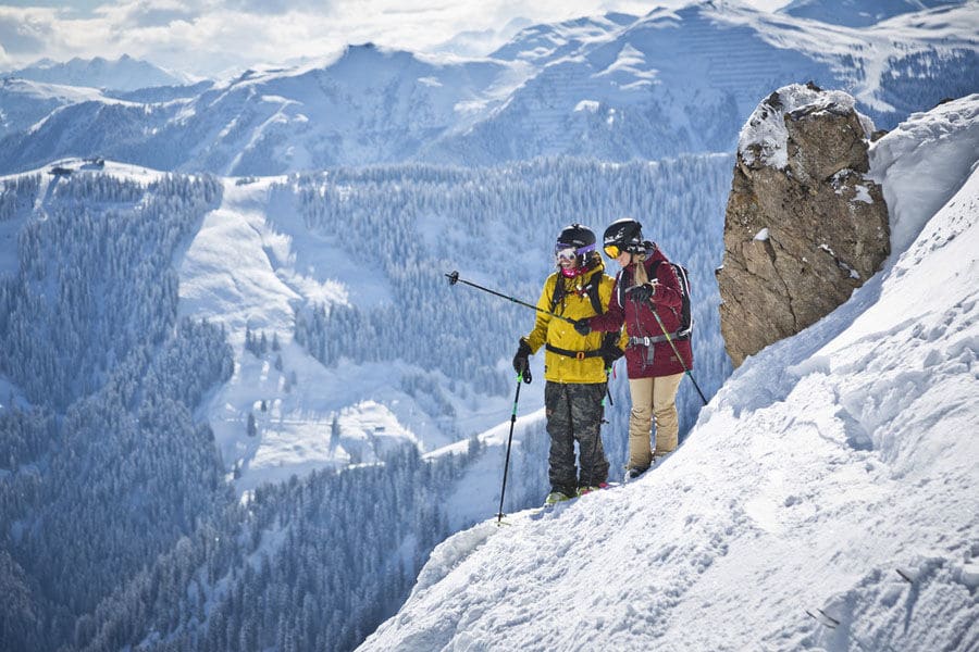 Paar steht auf steilem Schneehang mit Skiern