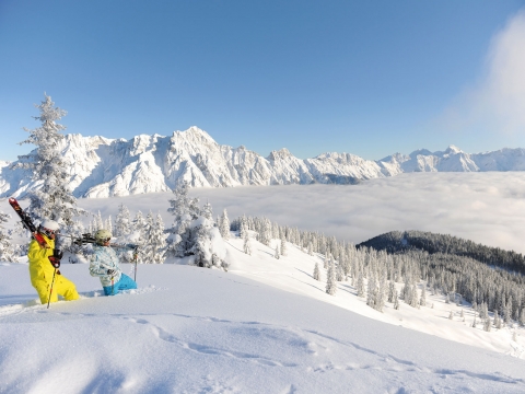 Paar wandern mit Ski auf den Schultern durch Tiefschnee