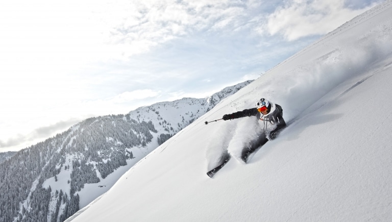 Skifahrer fährt steilen Schneehang hinunter