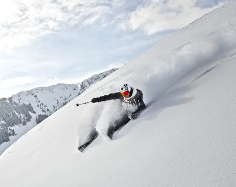 Wintersport Skifahren Skifahrer fährt steilen Schneehang hinunter