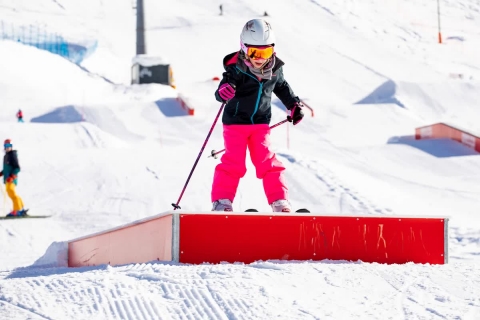Mädchen fährt über kleine Rampe mit Skiern