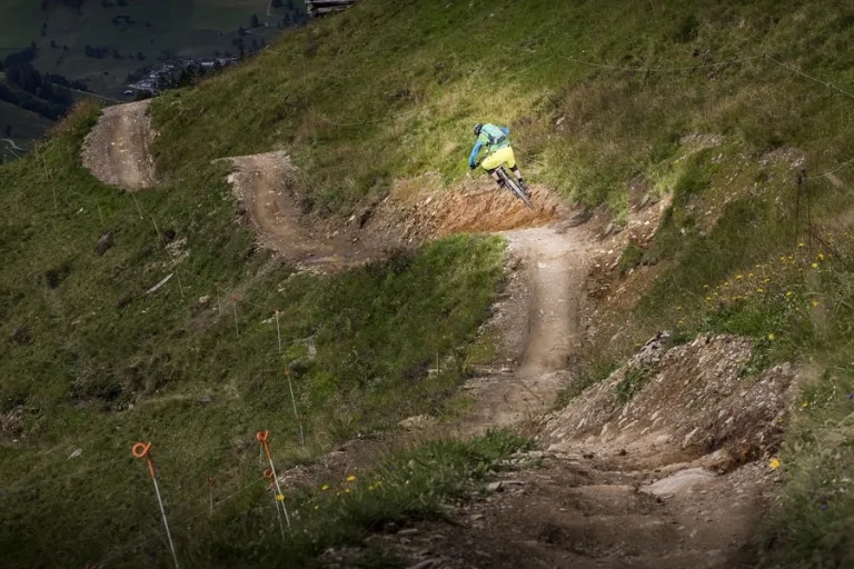 Bikeguide Mann springt gemeinsam mit Rad über Hügel