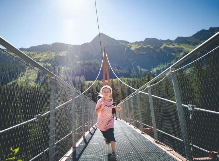 Mädchen läuft freudig über Golden Gate Bridge der Alpen