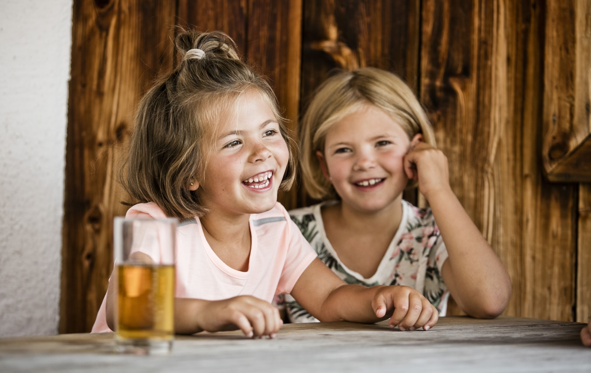 2 Mädchen sitzen lachend an Tisch