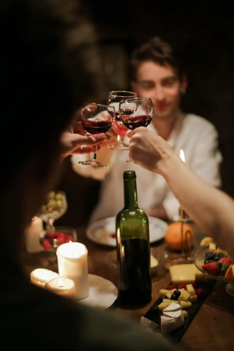 Wein zum Abendessen 3 Leute an Esstisch stoßen mit Weingläsern an