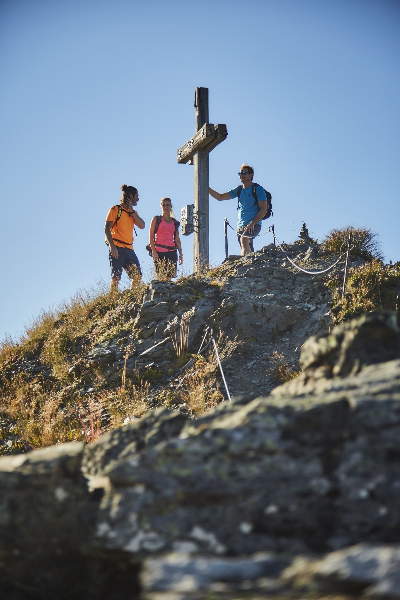 3 Wanderer stehen bei Gipfelkreuz