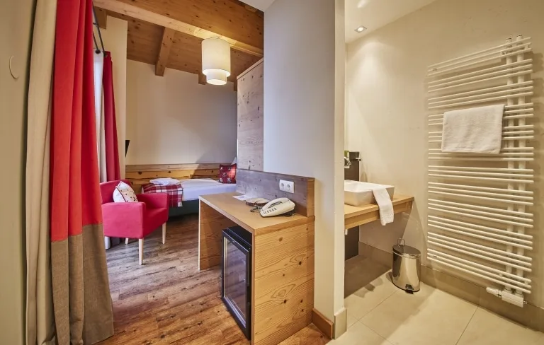 Überblick Einzelzimmer Blick in ein Einzelzimmer mit einem Bett sowie einer Minibar und dem Badezimmer