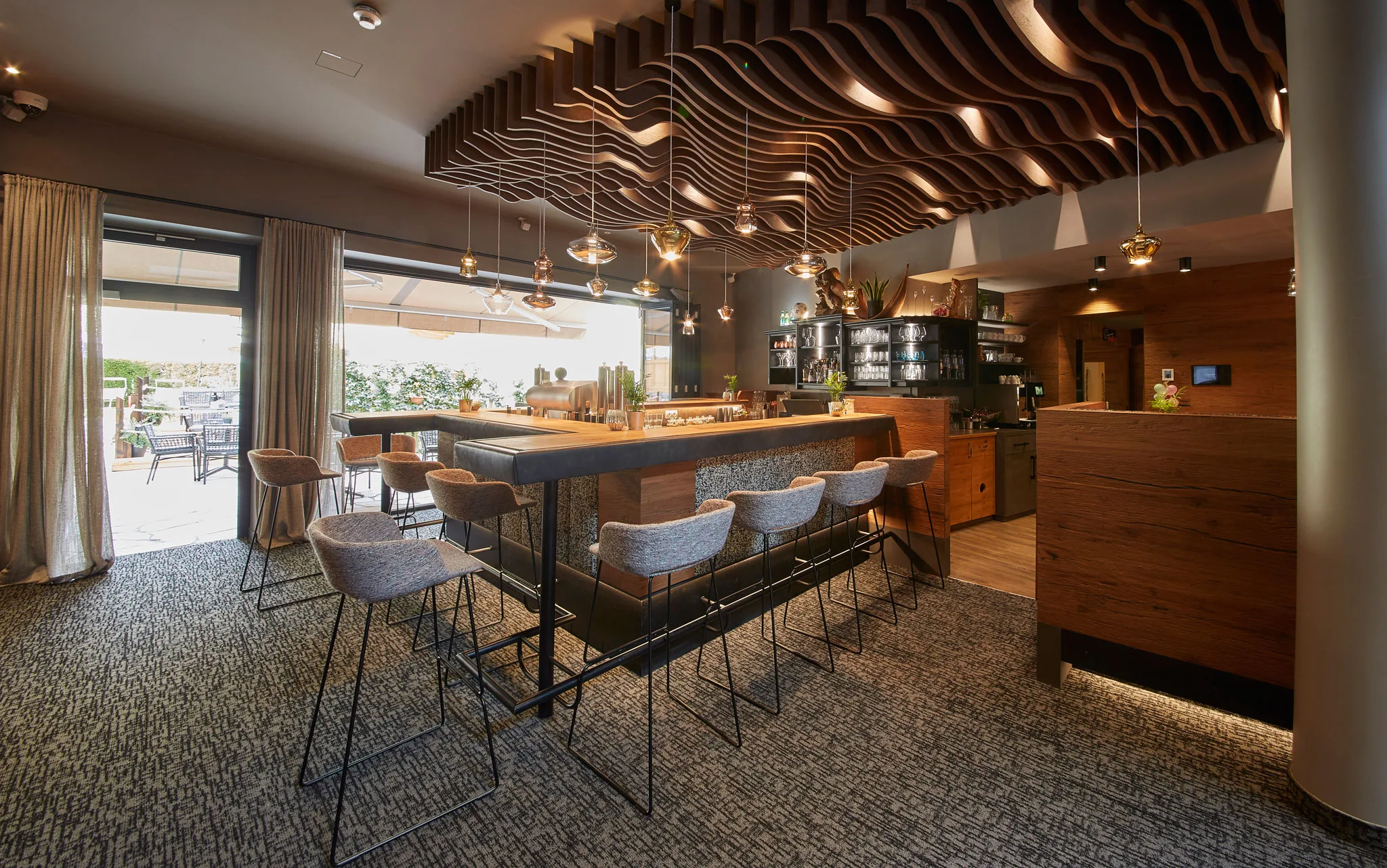 6677 Ein Blick auf die Bar mit Hochstühlen rundherum und stylischen Deckenleuchten.