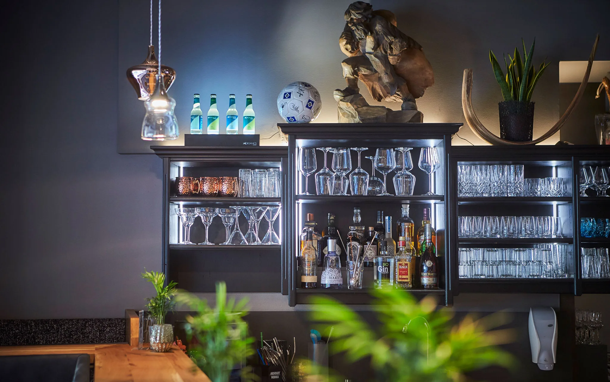 6674 Cocktailgläser und verschiedene Flaschen stehen in der Vitrine hinter der Bar