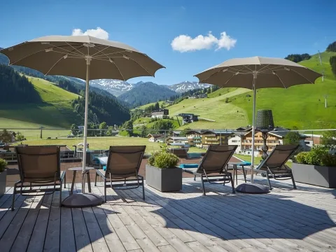 Sonnenterrasse mit Schirmen Sonnenschirme, Sonnenliegen und einen tolle Aussicht auf die umliegende Bergwelt