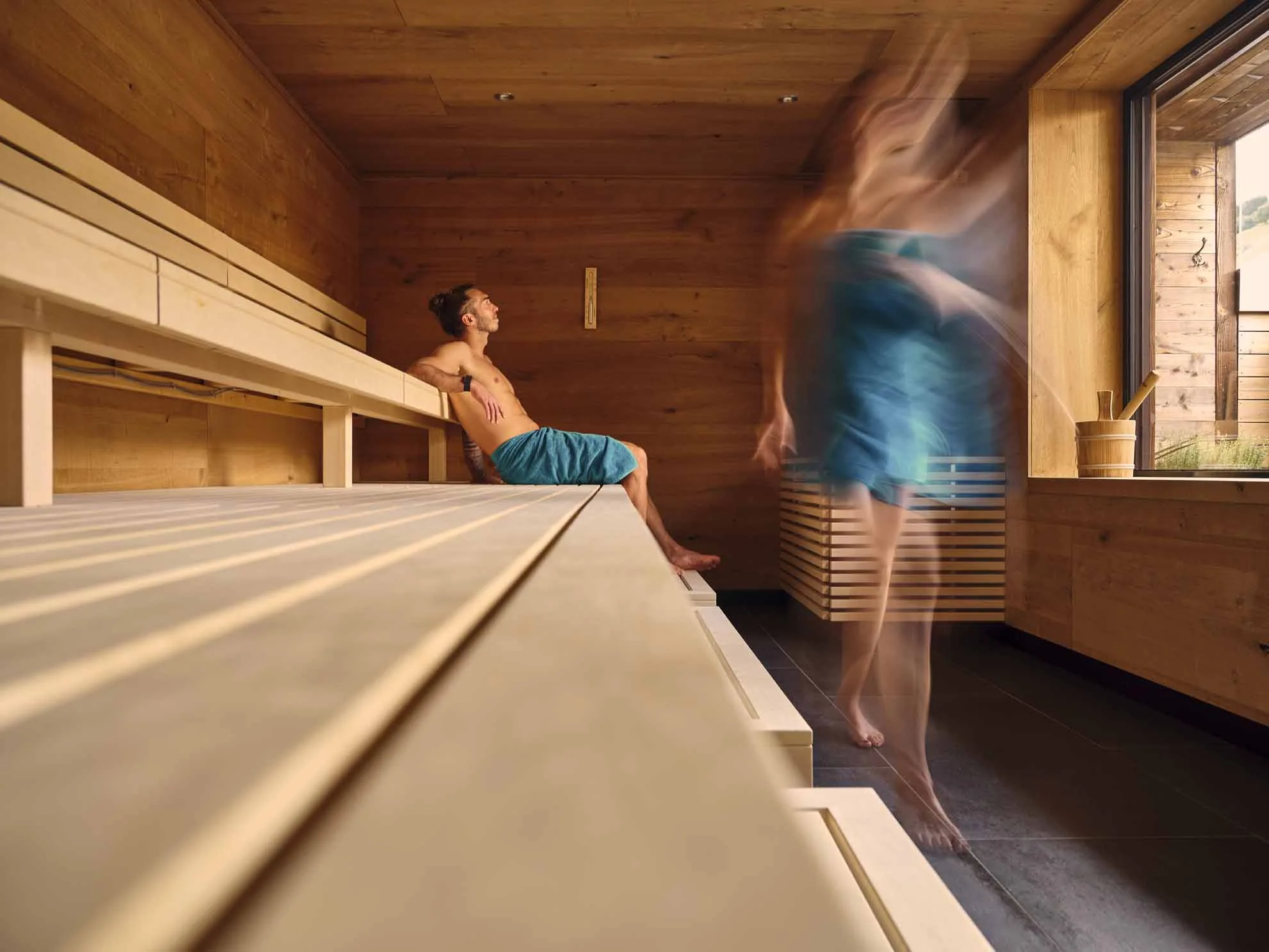 6914 Eine Person sitzt in der Sauna und eine geht gerade hinaus