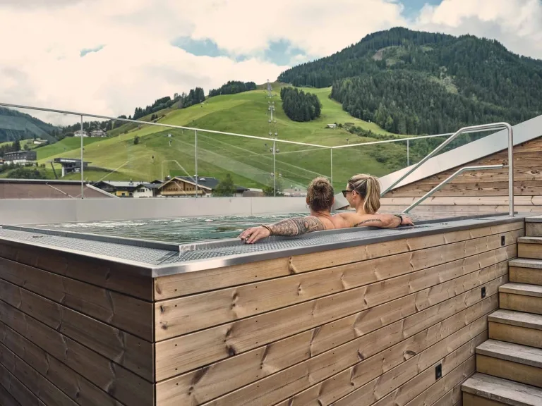 Whirlpool auf der Terrasse mit Aussicht Eine Frau und ein Mann sitzen im Rooftop Whirlpool