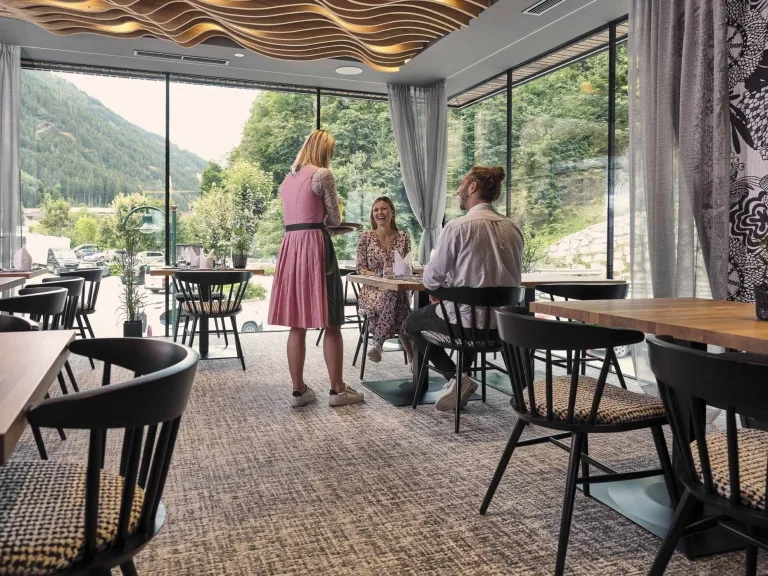 Der Restaurantbereich im Hasenauer Eine Restaurantkraft serviert Getränke an einen Tisch