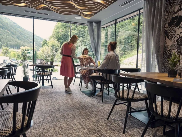 Service im Restaurant des Hotel Hasenauer Eine Restaurantkraft serviert das Essen an einen Tisch im Restaurant