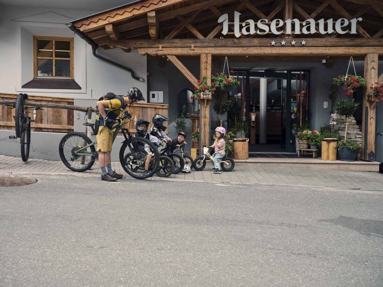 Ein Erwachsener Bike und Kinder mit Bike stehen vor dem Hotel Hasenauer