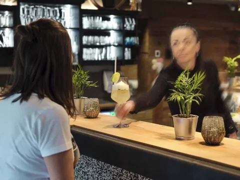 Cocktail an der Bar Frau serviert einen Cocktail im Glas an eine Frau an der Bar