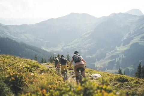 E-Bike-Touren in Saalbach Hinterglemm 3 Personen am E-Bike fahren den Berg hinunter