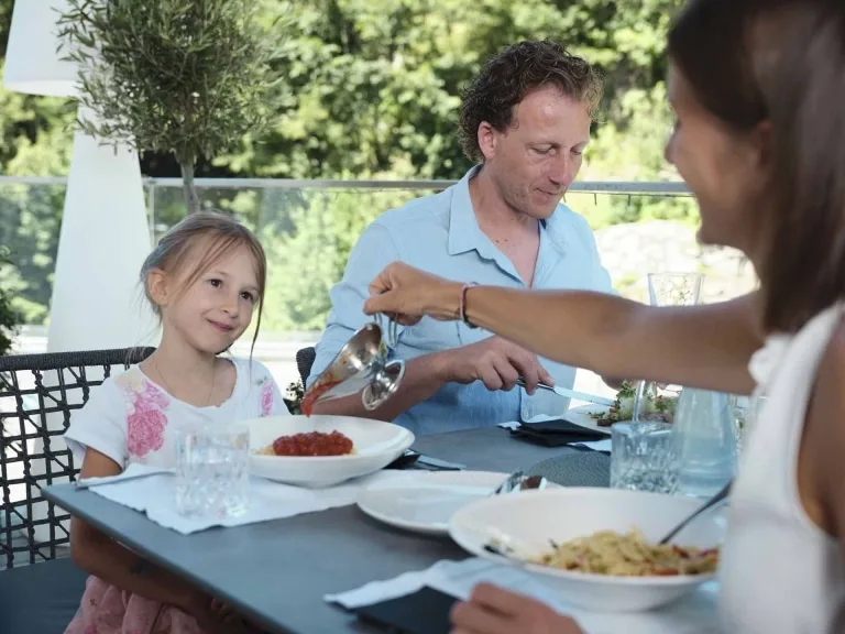 Mittagessen mit der Familie Mutter macht die Tomatensauce über die Spaghetti der Tochter.