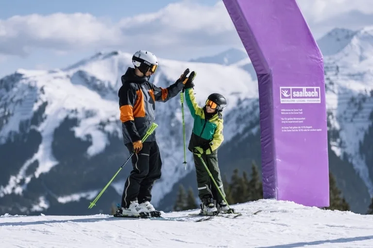Familienurlaub _ Family Holiday Skicircus Saalbach Hinterglemm Leogang Fieberbrunn (6) Kind und Vater klatschen ein in Skiaustrüstung
