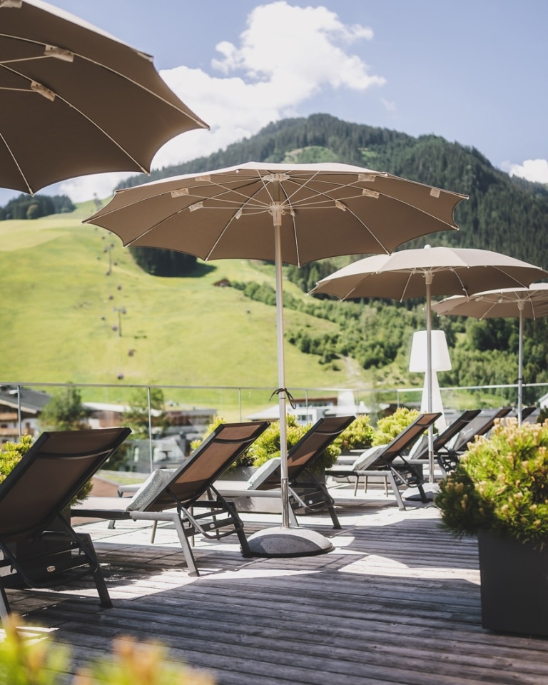 HOTEL HASENAUER Aufgespannte Schirme über Liegen mit Bergblick